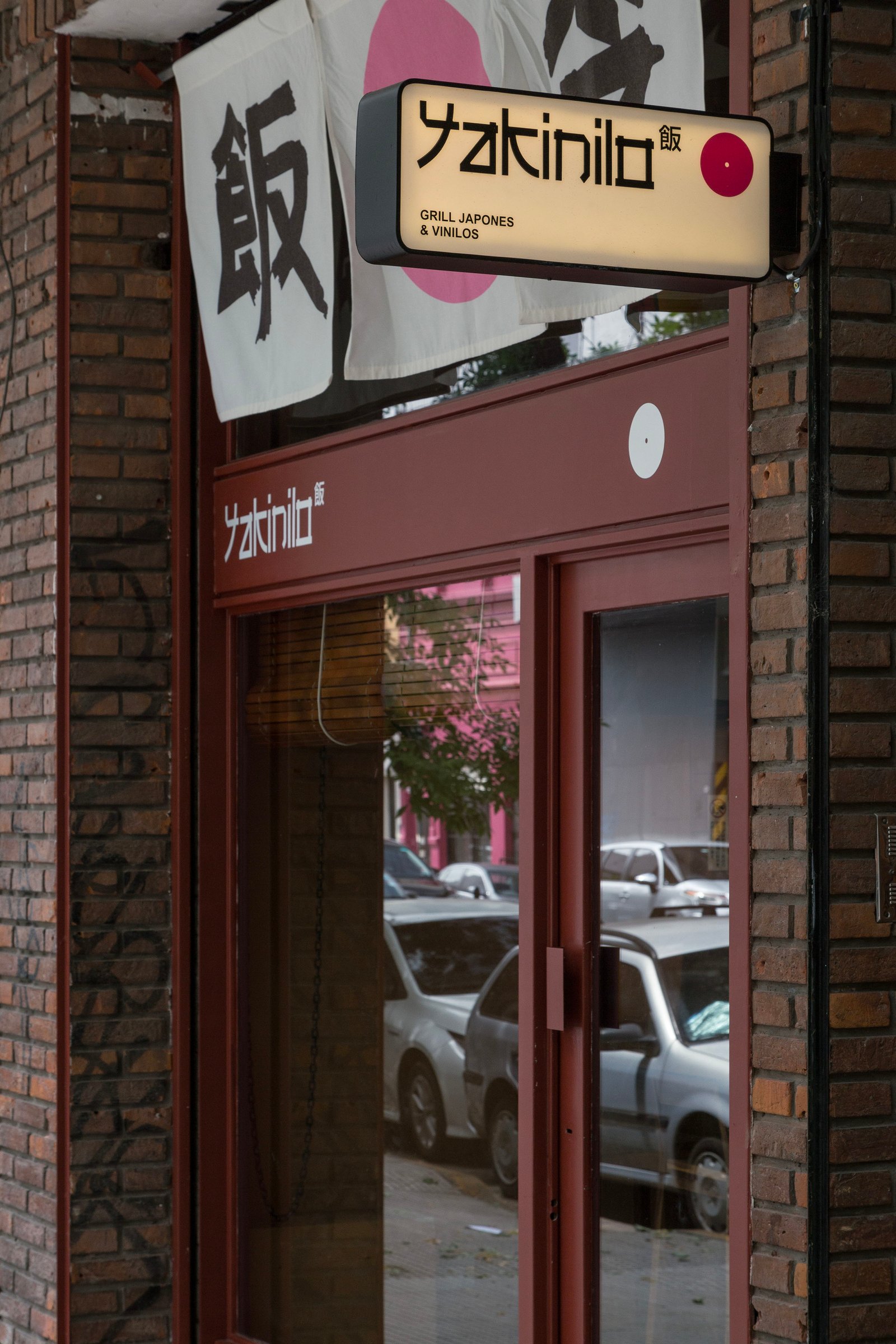fachada de restaurante com placa iluminada e tijolos expostos — projeto Yakinilo, por Estudio YME, em Av. Dorrego 1551